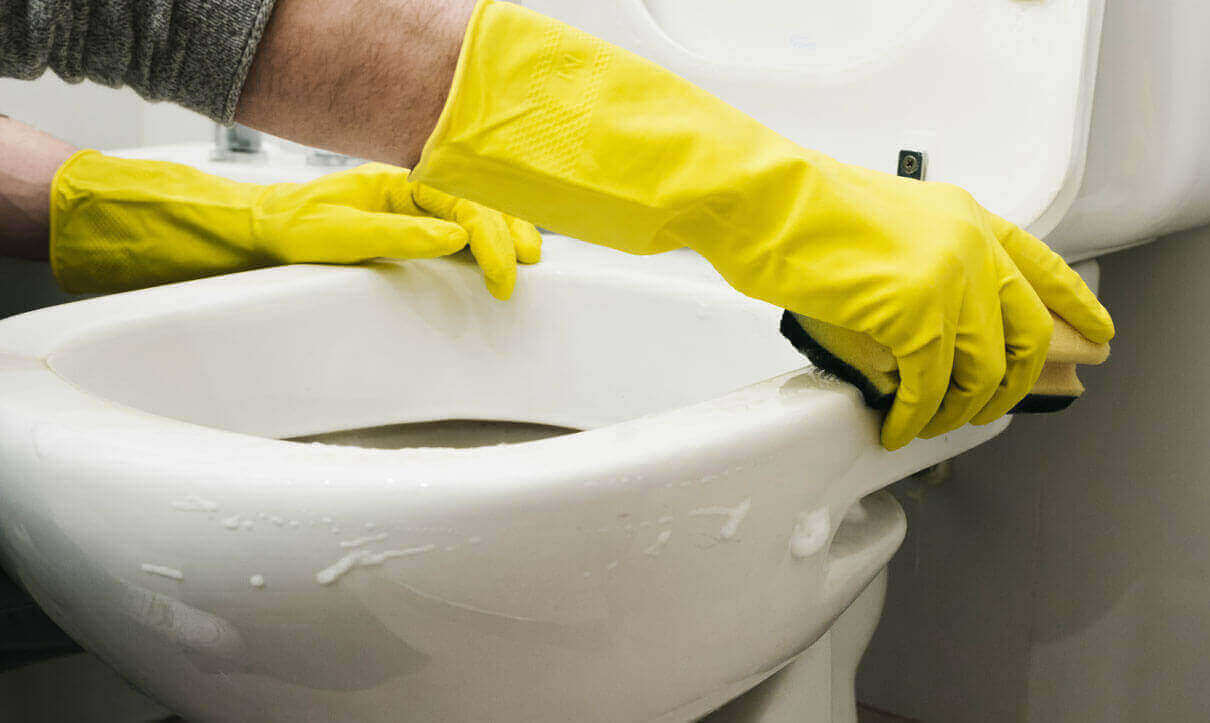 hands with protective gloves cleaning toilet