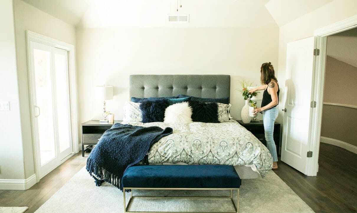 Maid standing by bed in bedroom